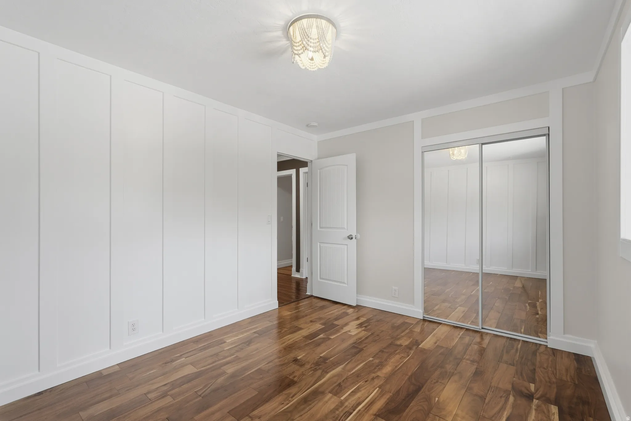 Bright room featuring wood-finish flooring, white paneling, and a mirrored sliding closet door