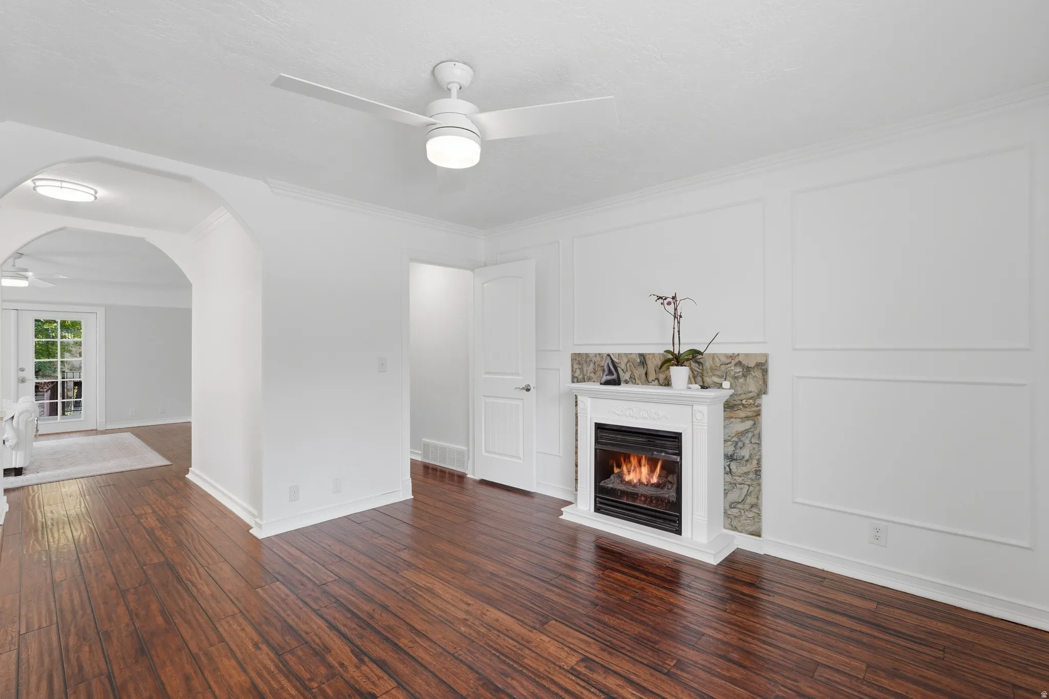 Spacious room featuring wood-finish flooring and a white ceiling fan with integrated lighting