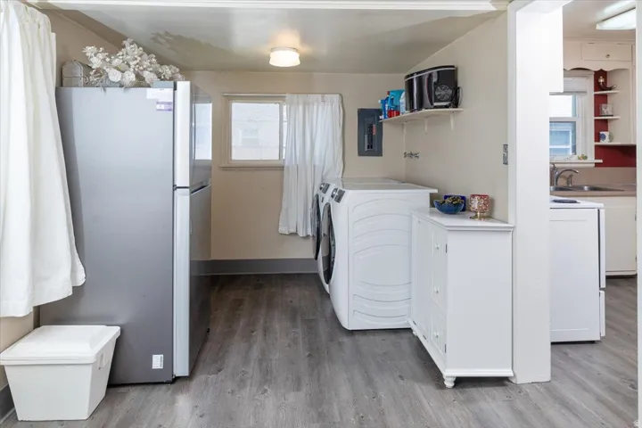 Laundry area featuring wood-finish flooring, a window with curtains, and a built-in wall shelf