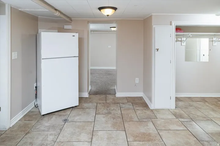 Tiled flooring with neutral-toned walls, featuring a built-in storage cabinet and an open closet with shelving