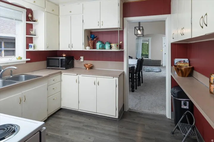 Kitchen featuring white cabinetry, wood-finish flooring, and a double-basin stainless steel sink