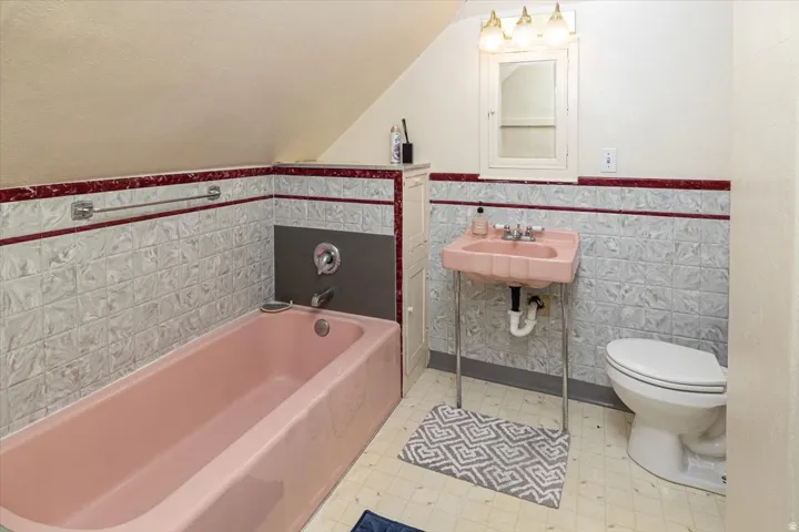 Bathroom featuring a pink bathtub, matching basin sink, and white toilet