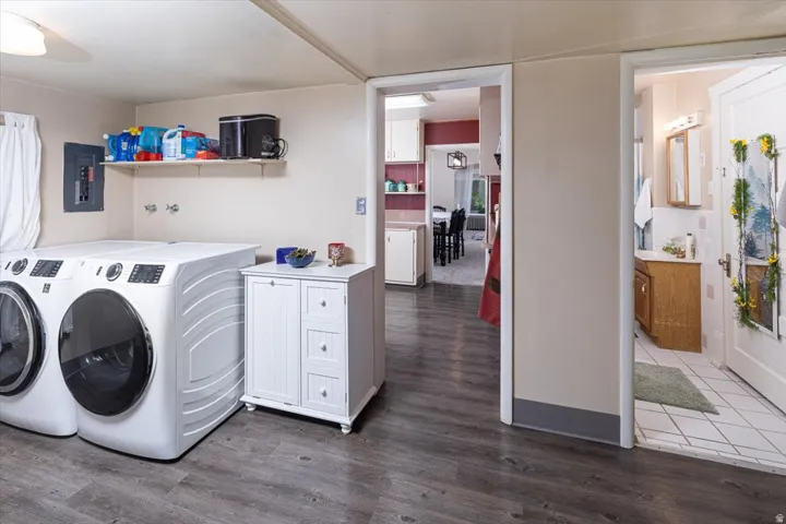 Laundry area with wood-finish flooring, an electrical panel, and an overhead shelf