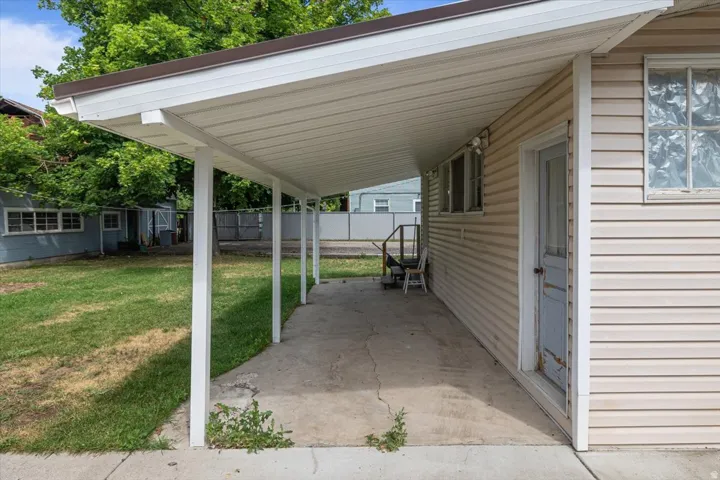 Covered patio area featuring a concrete slab, white support columns, and beige horizontal siding on the exterior wall