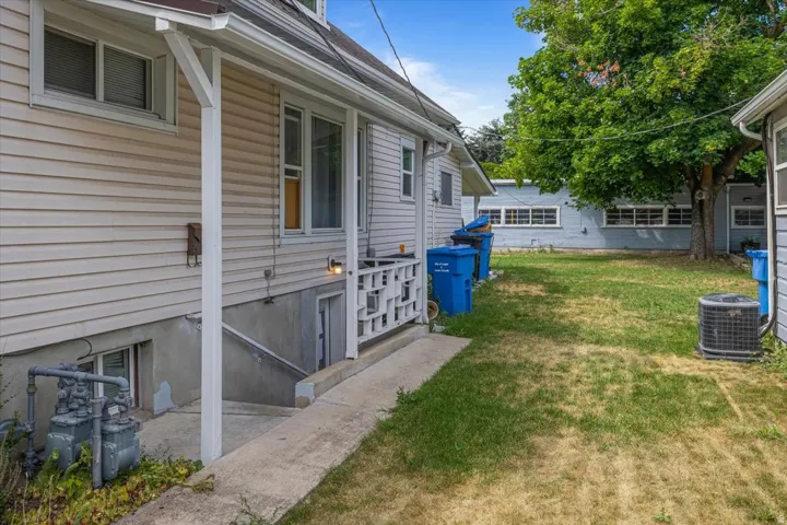 Side entry: Unit #2. Exterior siding with multiple windows and a concrete walkway leading to a basement apartment.