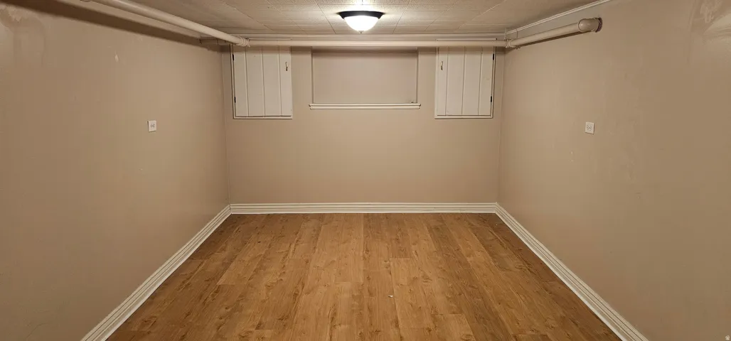 Finished room featuring wood-finish flooring, neutral wall tones, and white baseboards