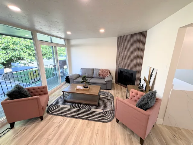 Living space featuring wood-finish flooring, recessed lighting, and a contemporary fireplace with a vertical slat surround