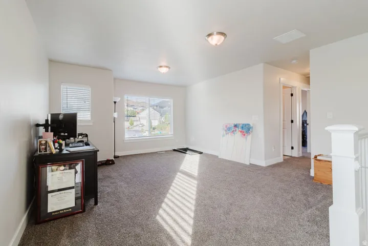 Spacious carpeted room featuring multiple windows with blinds, providing ample natural light