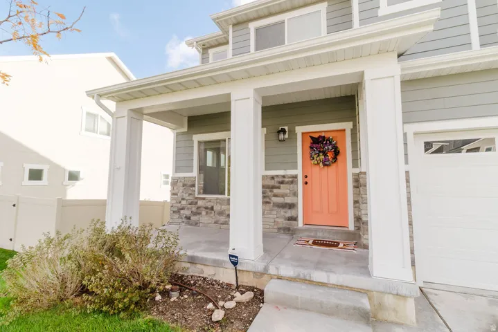 Covered front porch featuring white columns and stone veneer detailing
