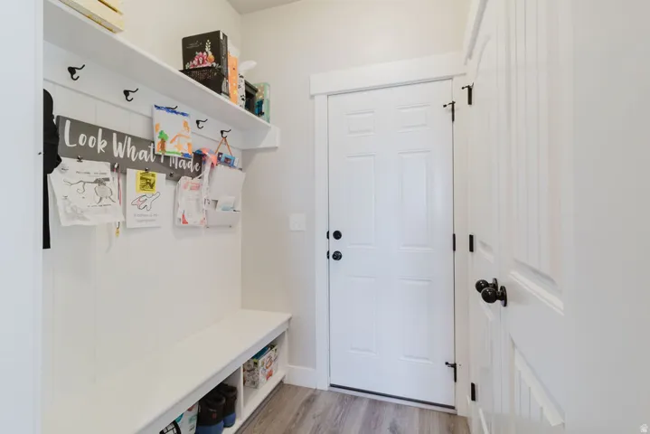 Entryway featuring a built-in bench with integrated shelving, beadboard wall paneling, and a storage shelf with coat hooks