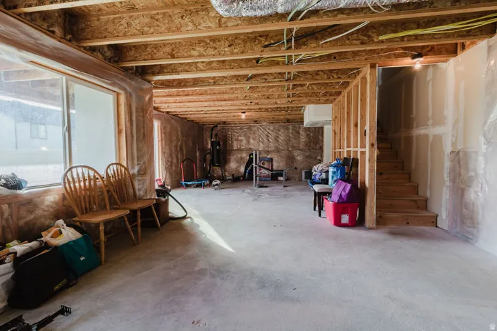 Unfinished basement featuring exposed wood joists and subflooring, framed walls, and concrete flooring