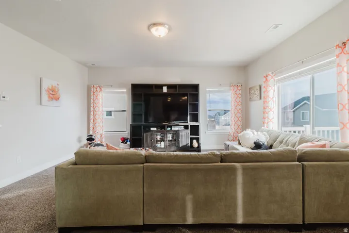 Inviting living area featuring a built-in media center, large windows, recessed lighting, and carpeted flooring