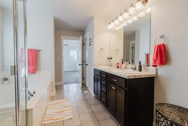 Bathroom featuring dual vanities with dark wood cabinetry, light-toned countertops, and undermount sinks