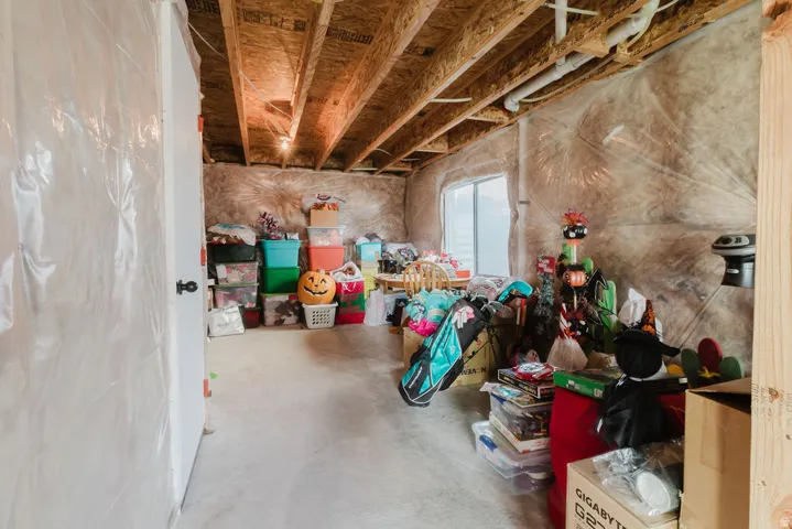 Unfinished basement space featuring exposed wood joists, concrete flooring, and a single window