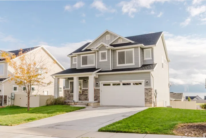 Contemporary two-story residence featuring light gray siding and stone accents