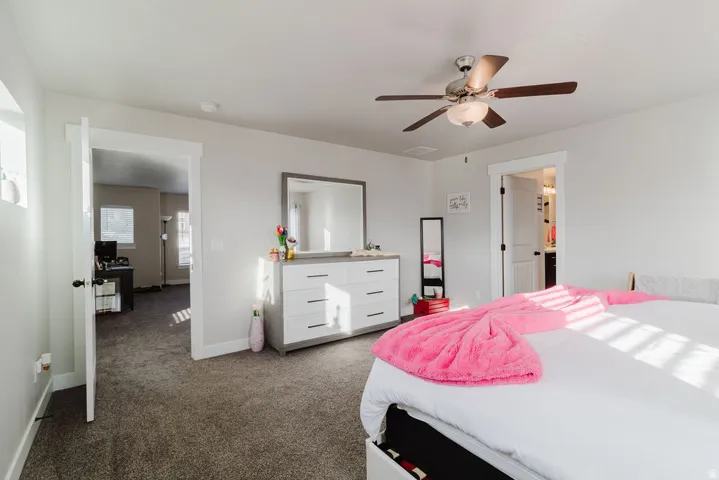 Carpeted bedroom with a ceiling fan, recessed lighting, and a white trim doorway opening to an adjacent space