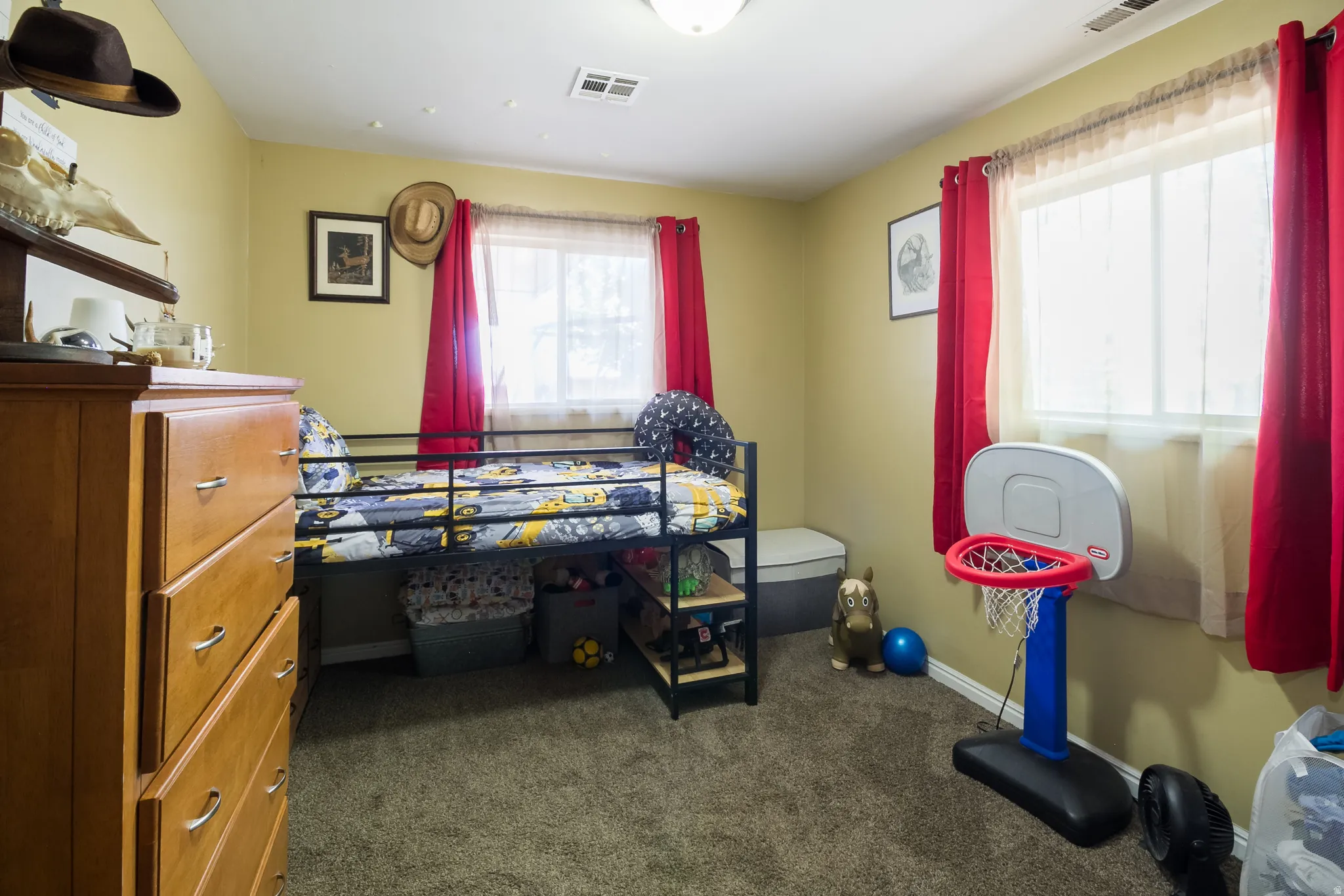 Carpeted room with a ceiling-mounted light fixture, two windows, and light-toned walls
