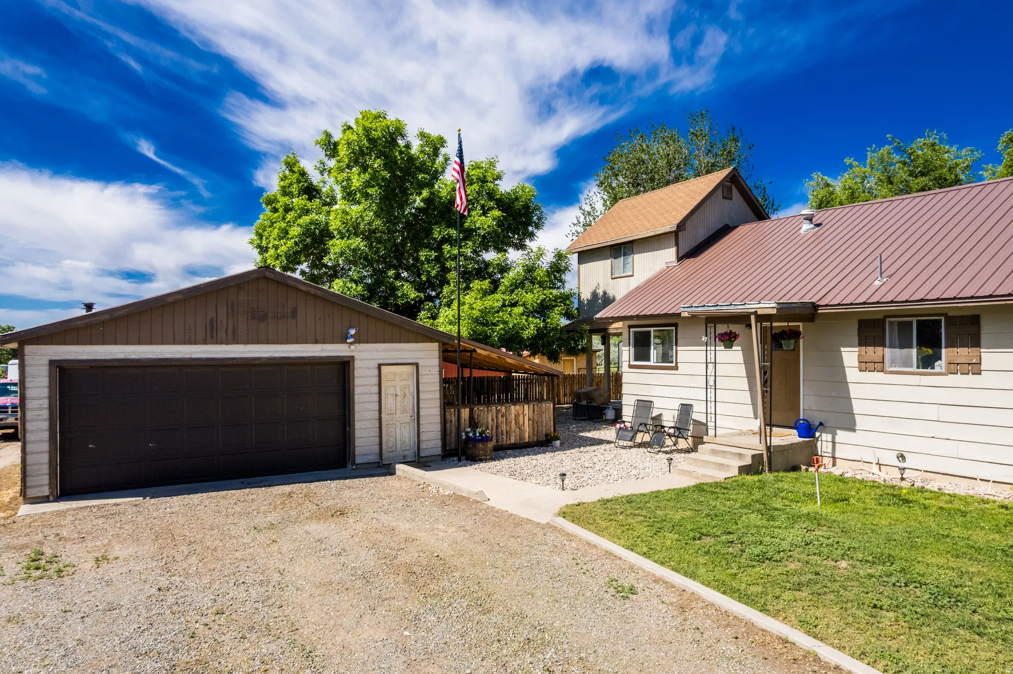 Detached garage with a side entry door, gravel driveway, and a fenced patio area