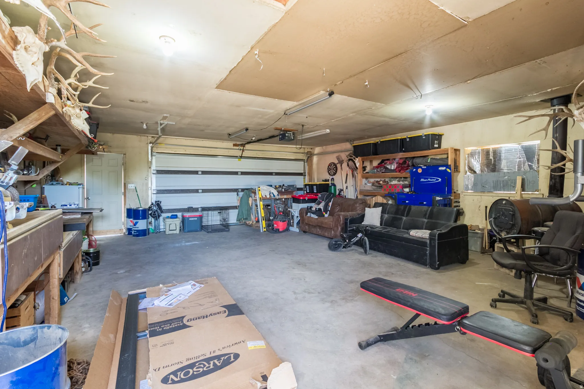 Spacious garage featuring a large roll-up door, concrete flooring, and built-in shelving