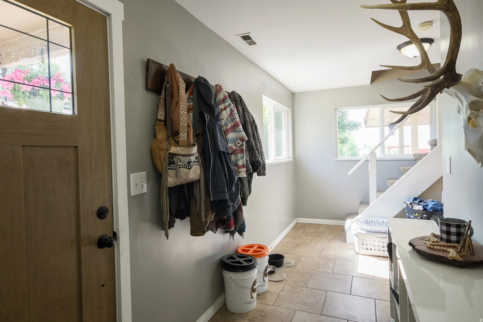Foyer featuring a Craftsman-style entry door with divided lites, tile flooring, and a built-in coat rack