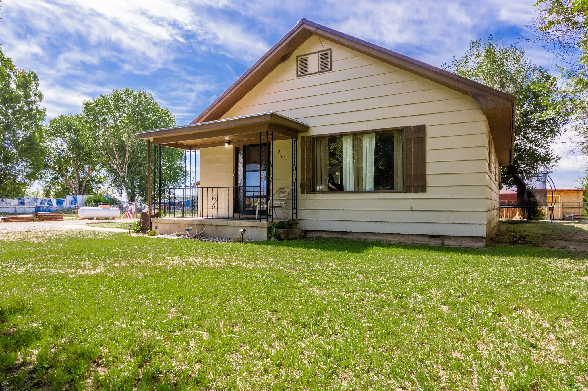 Exterior featuring siding, a covered front porch with wrought iron railings, and a front-facing window with shutters