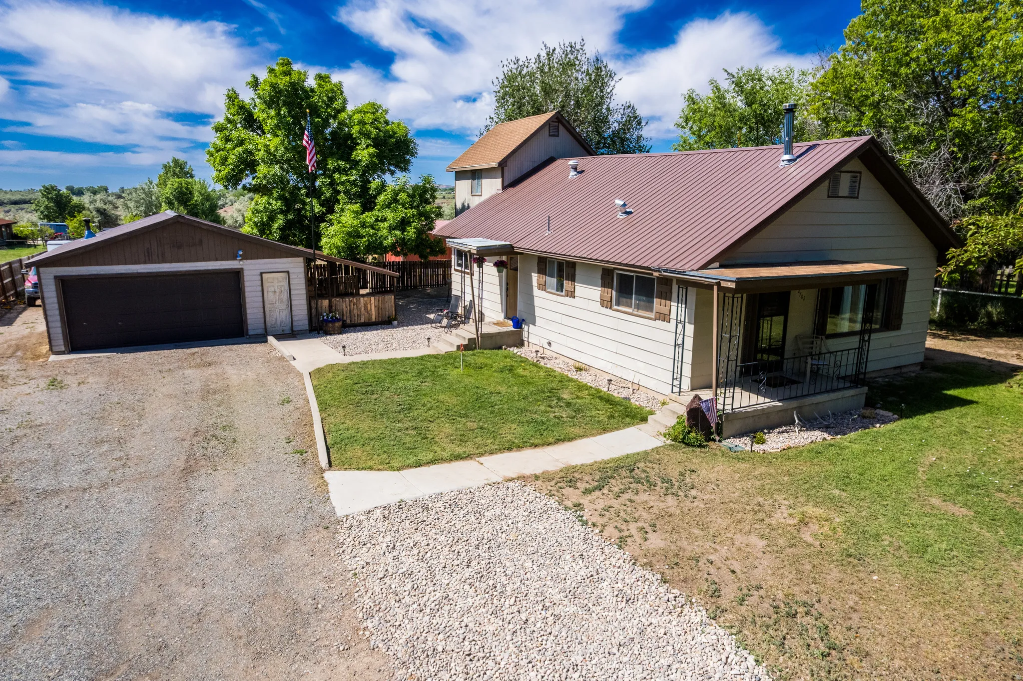 Property featuring a detached two-car garage, gravel driveway, and covered front porch