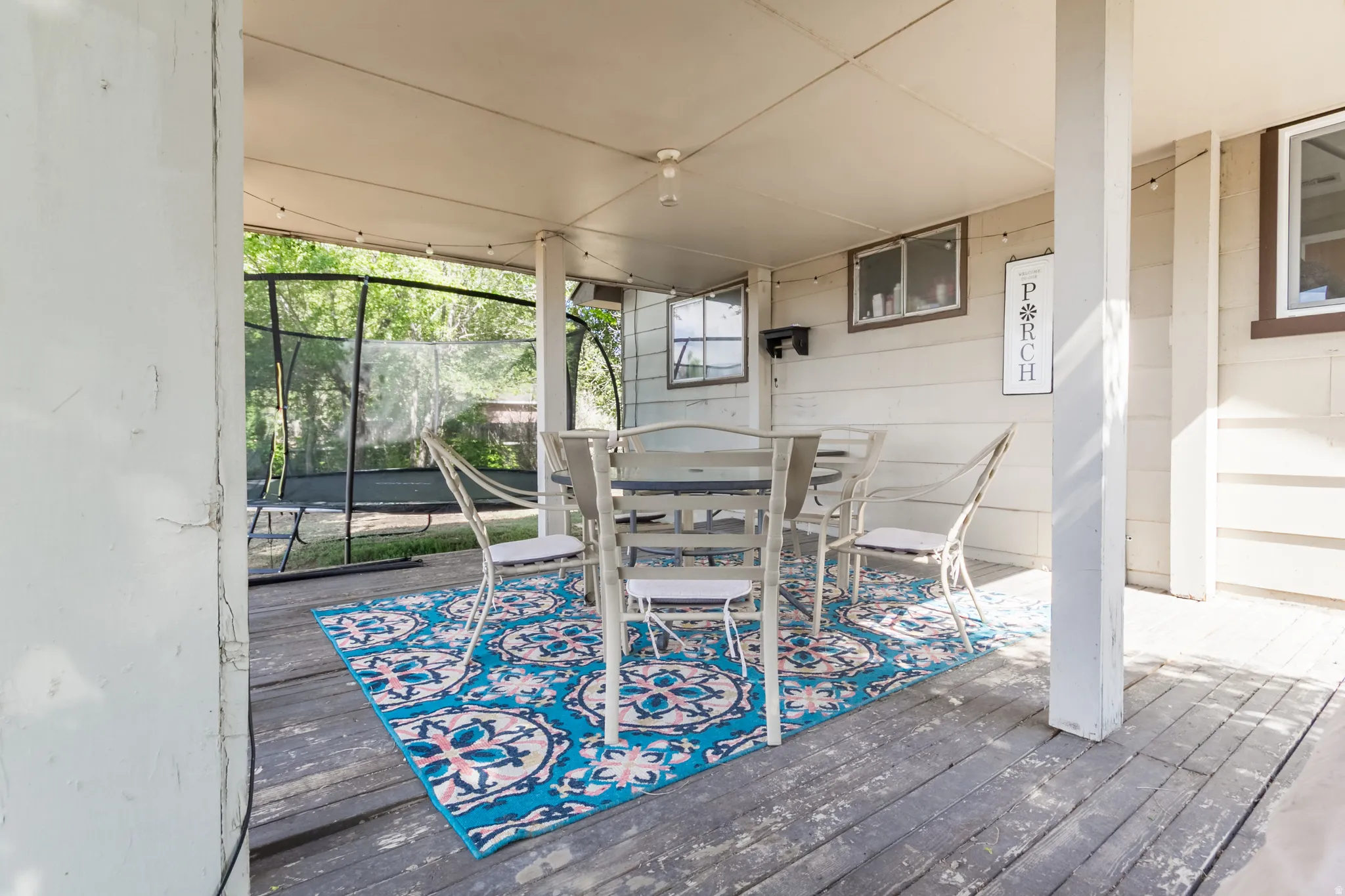 Covered wood deck featuring painted siding and multiple windows