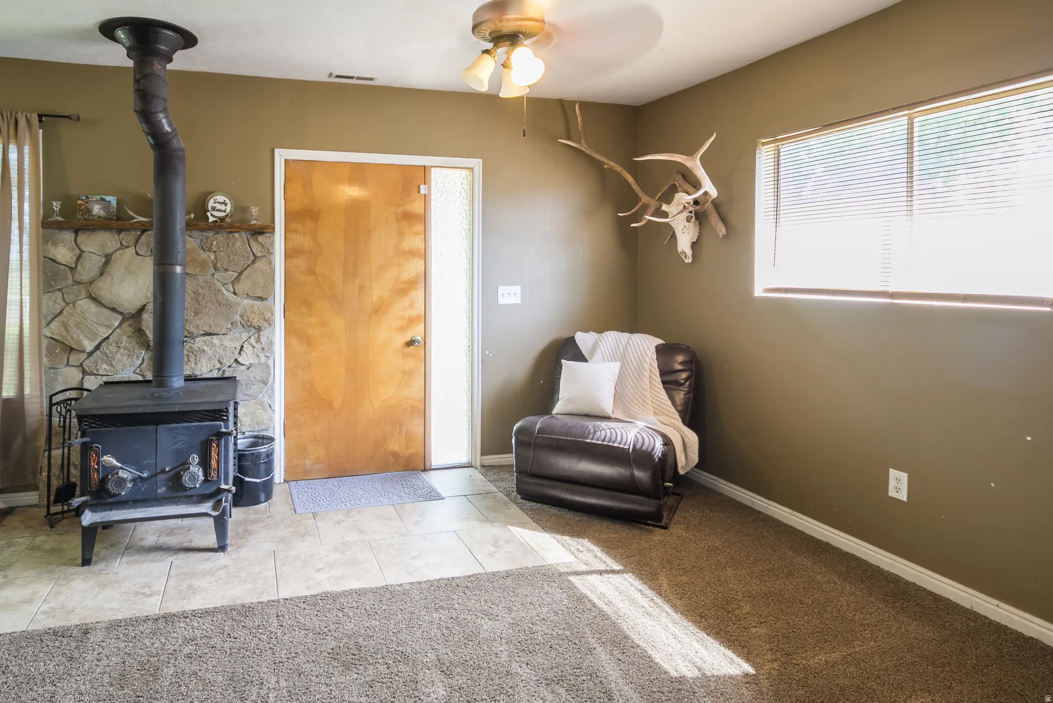 Wood-burning stove with a stone surround, complemented by a light wood entry door with a frosted glass sidelight