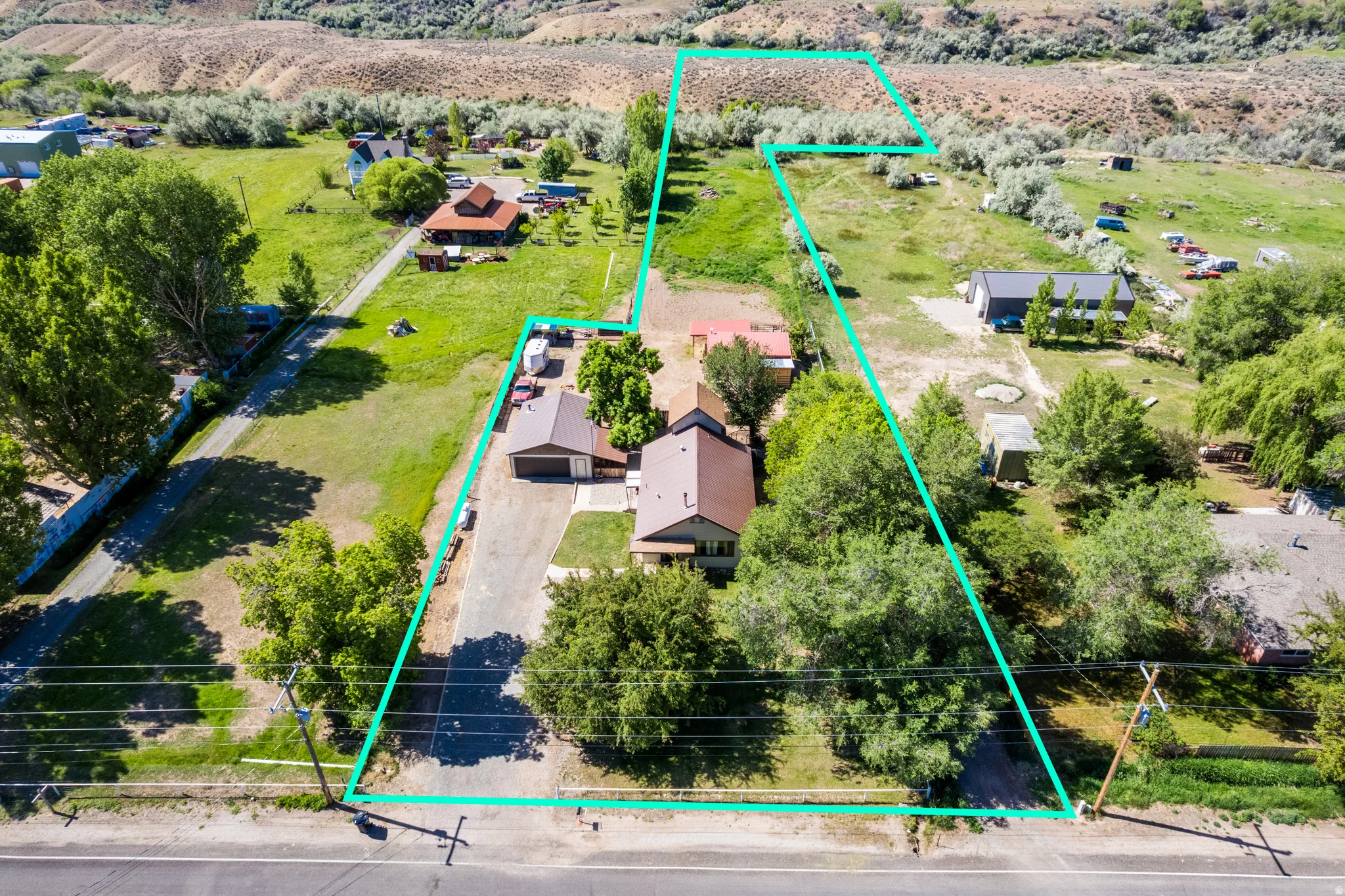 Expansive property featuring a brown-roofed residence, extensive green landscape, mature trees, paved driveways, and a distinct boundary line