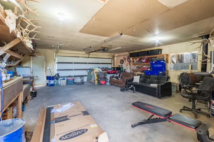 Spacious garage featuring a large roll-up door, concrete flooring, and built-in shelving