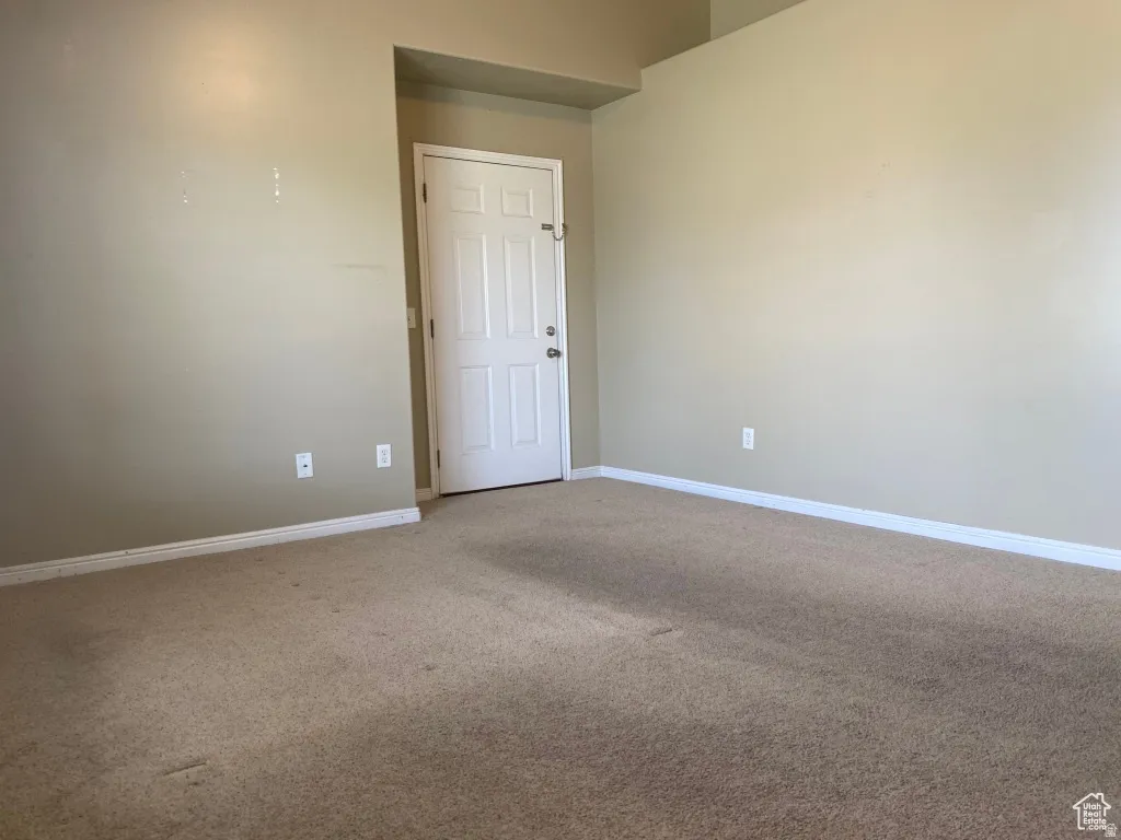 Primary Bedroom: Neutral-toned walls complement the full carpeting in this room, featuring a white paneled door with hardware