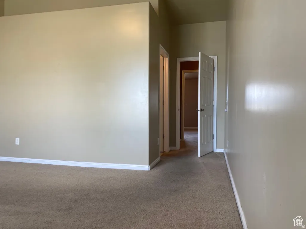 Primary Bedroom: Neutral-toned walls complement the brown carpeted flooring throughout the space