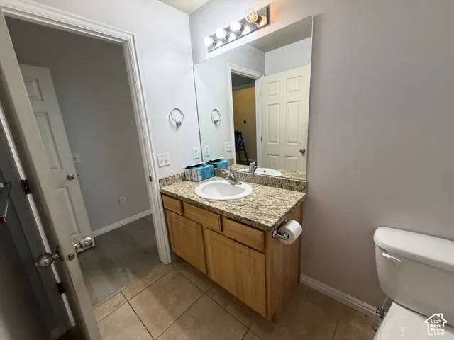 Primary vanity with a granite countertop, single basin sink, and cabinetry