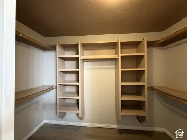 Primary custom built-in shelving, integrated hanging rods, LVP flooring, and crown molding