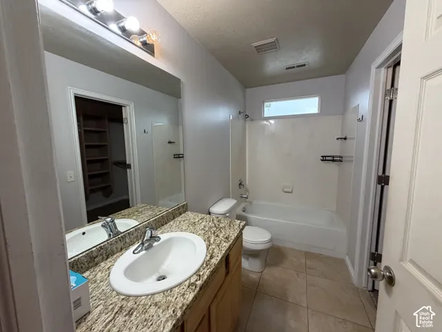 Primary bathroom featuring a vanity with a white oval sink, granite countertop, and wood-finish cabinetry