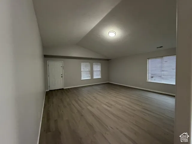 Spacious living room with LVP flooring, vaulted ceiling, and a large windows