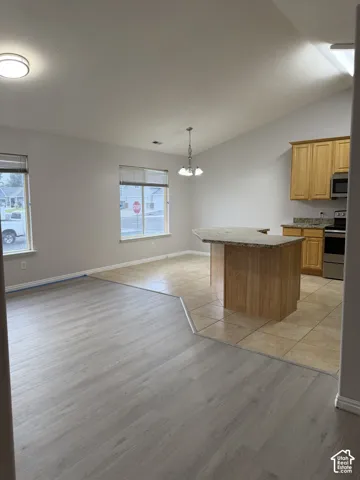 Vaulted ceiling, LVP flooring, tiled flooring, wood cabinetry, stone countertops