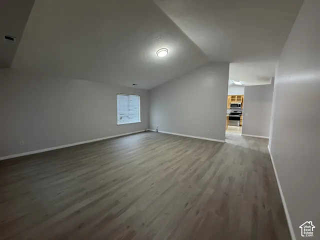 Spacious living room with LVP flooring, vaulted ceiling, and a large windows