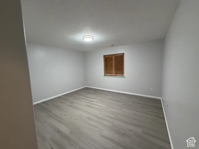 Bedroom 2 with neutral gray wall paint, LVP flooring, single window with blinds, ceiling-mounted light fixture, white trim