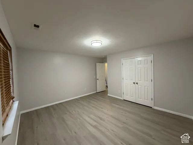 Recessed ceiling light fixture, wood-finish flooring, white bi-fold doors, white baseboards, and window with wood blinds