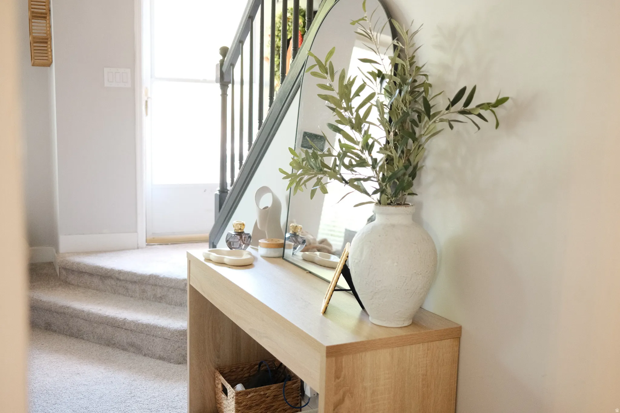 Staircase featuring carpeted treads and risers, a dark wood-finish handrail, and black balusters