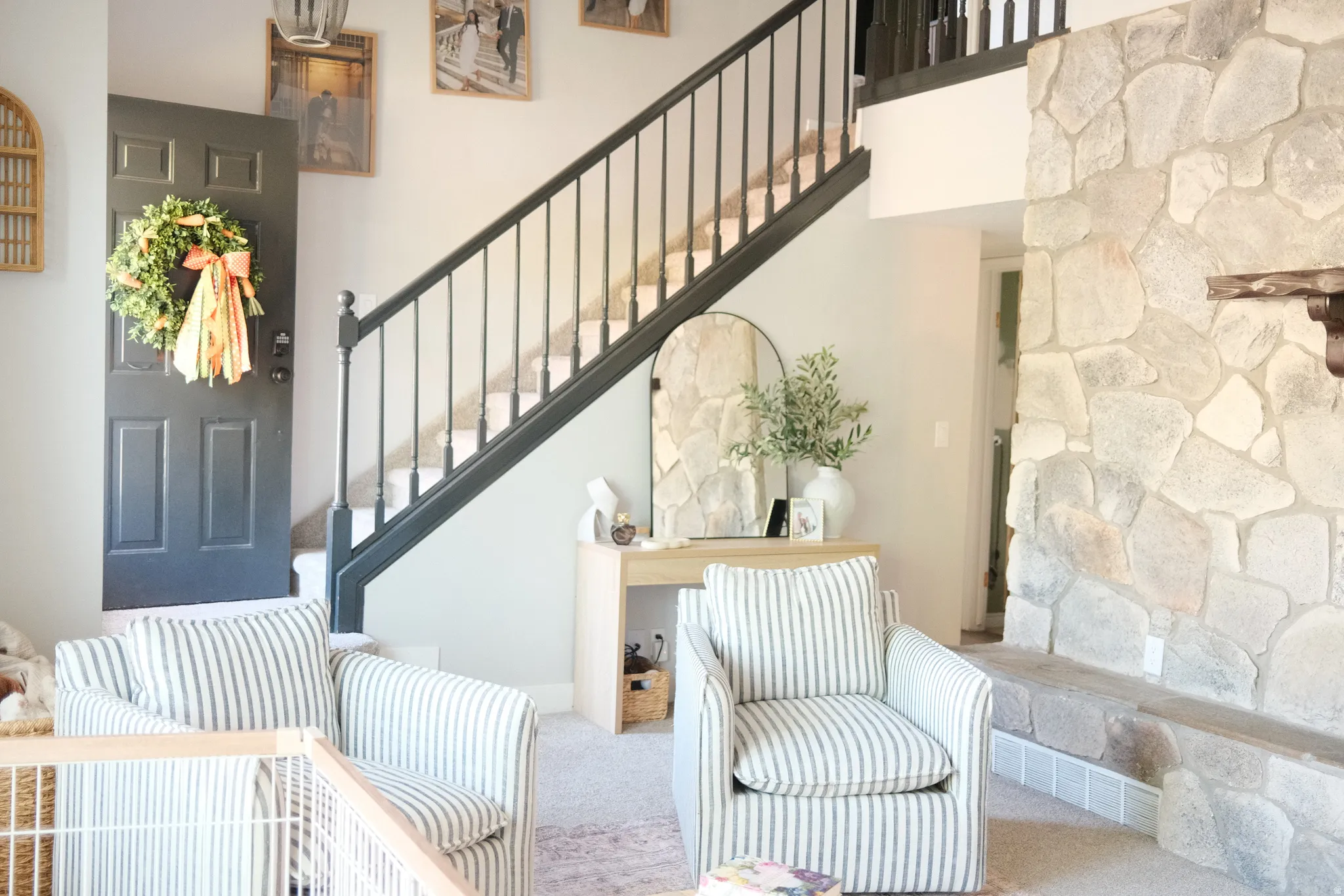 Foyer with a dark panel door, a black spindle staircase, and a floor-to-ceiling stone fireplace featuring a wood mantel