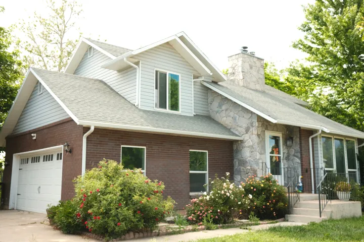 Multi-level residence featuring a prominent stone chimney and a combination of brick and siding exterior
