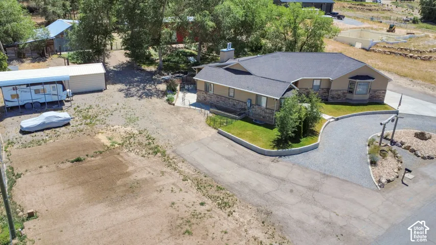 Ranch-style residence featuring a stone and stucco exterior, dark shingle roofing, and a curved gravel driveway