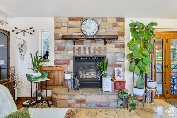 Stone-clad fireplace featuring an integrated firebox that can be loaded from the pation, custom carved mantle and raised hearth