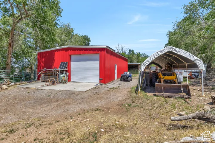 Red metal-sided outbuilding featuring a 10' white roll-up garage door and a side entry door