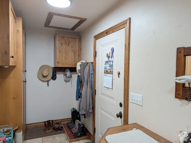 Utility space featuring wood-finish cabinetry, a built-in coat rack, and recessed ceiling lighting