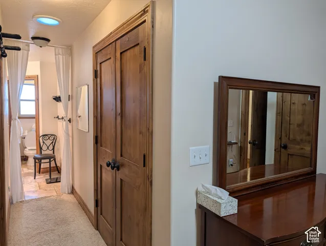 Hallway featuring wood-finish bi-fold doors, a recessed ceiling light, and a light-colored carpeted floor