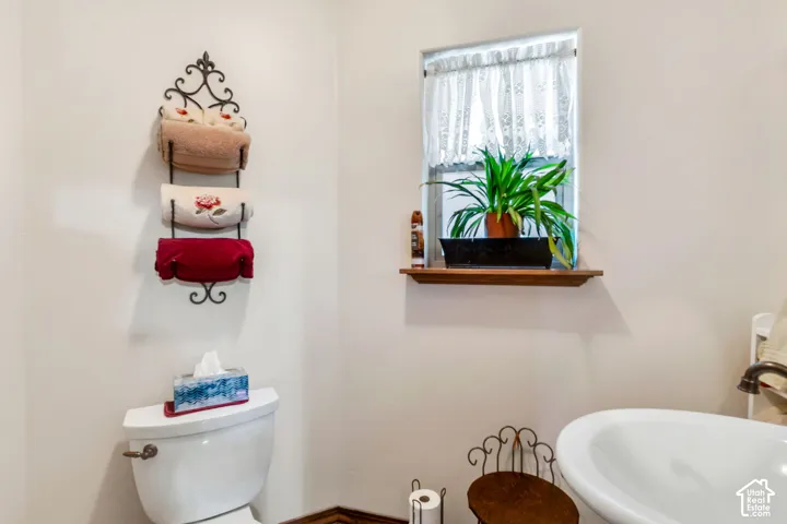Bathroom featuring a window with a wood sill, white walls, and a white toilet
