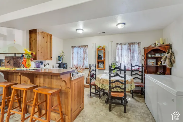 Basement Kitchenette with a wood-finish bar and overhead cabinetry, featuring a compact sink area